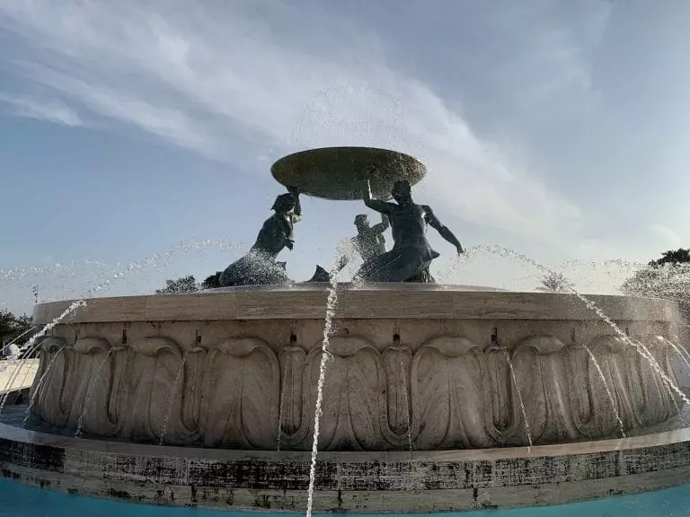 the huge tritons fountain with white marbe base and bronze sculpture in front of the valletta city gate