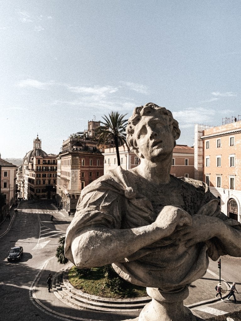 a romanesque sculpture in villa aldobrandini with modern rome city as background