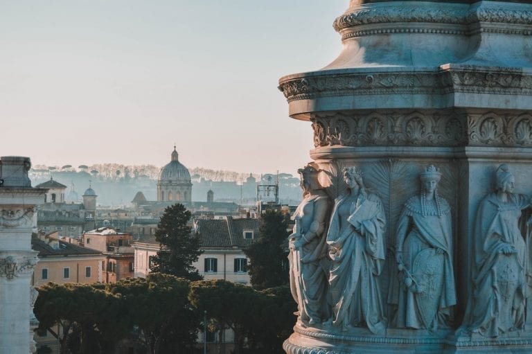 the details on the marble column in Rome with Rome city and Vatican as a background