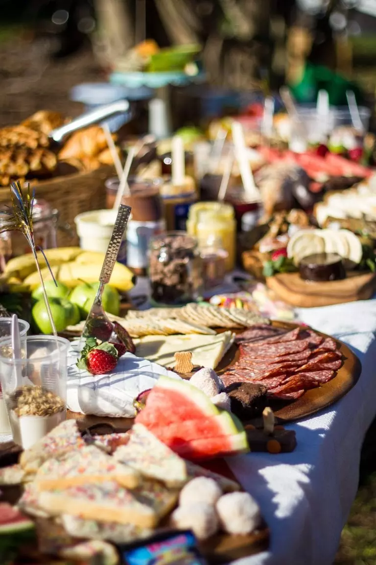 an italian themed dinner party needs a table covered fully by different snacks and food