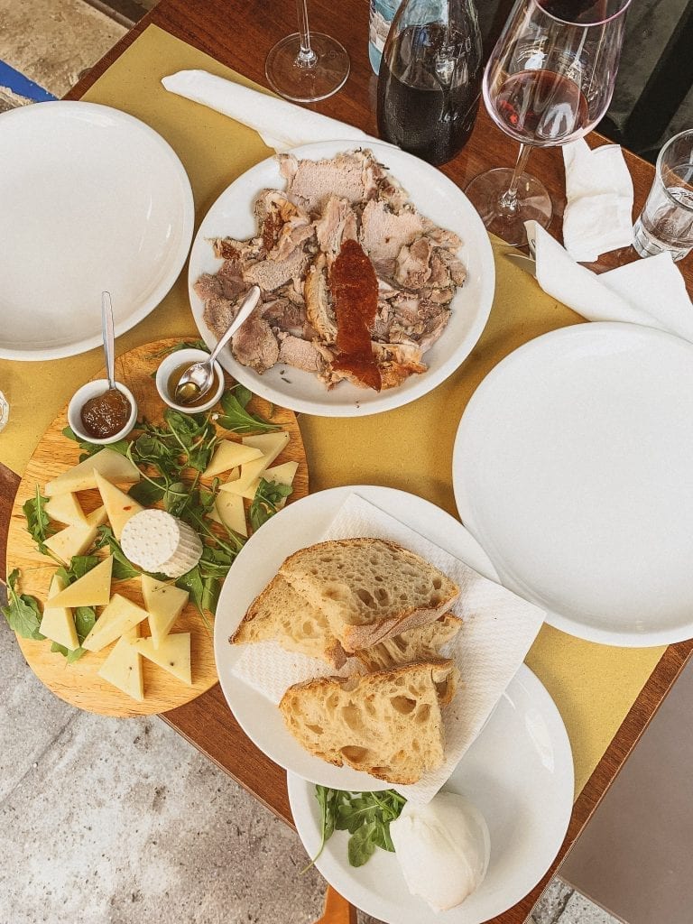 Enjoy the Fraschetta type of Aperitivo in Rome with porchetta, cheese and meat platter, and chilled red wine in the out-of-the-city neighborhood